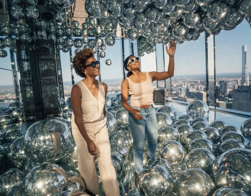 two women standing in a room with many silver balls