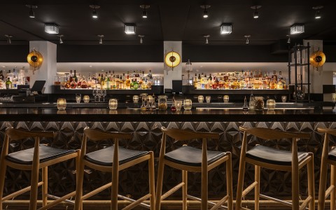 a bar with a row of stools and bottles