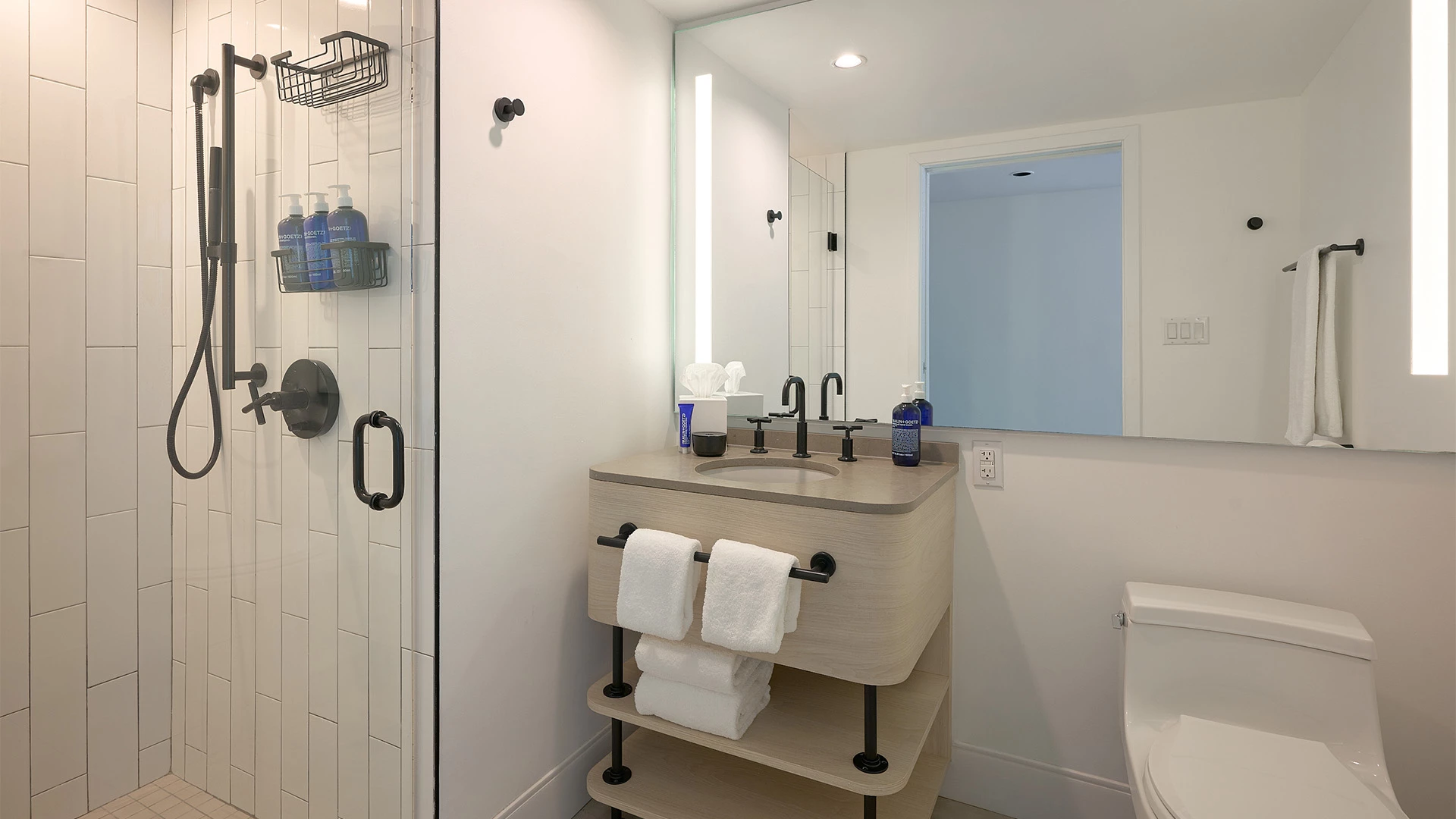 A modern bathroom with a shower, sink, toilet, and towels