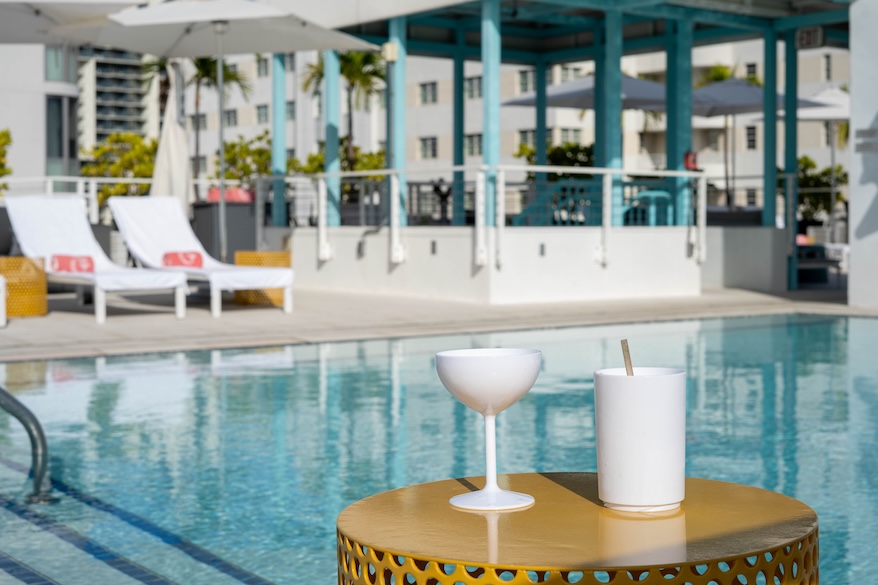 a white drink on a table next to a pool