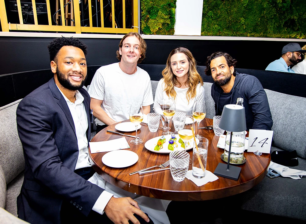 a group of people sitting around a table with food and drinks