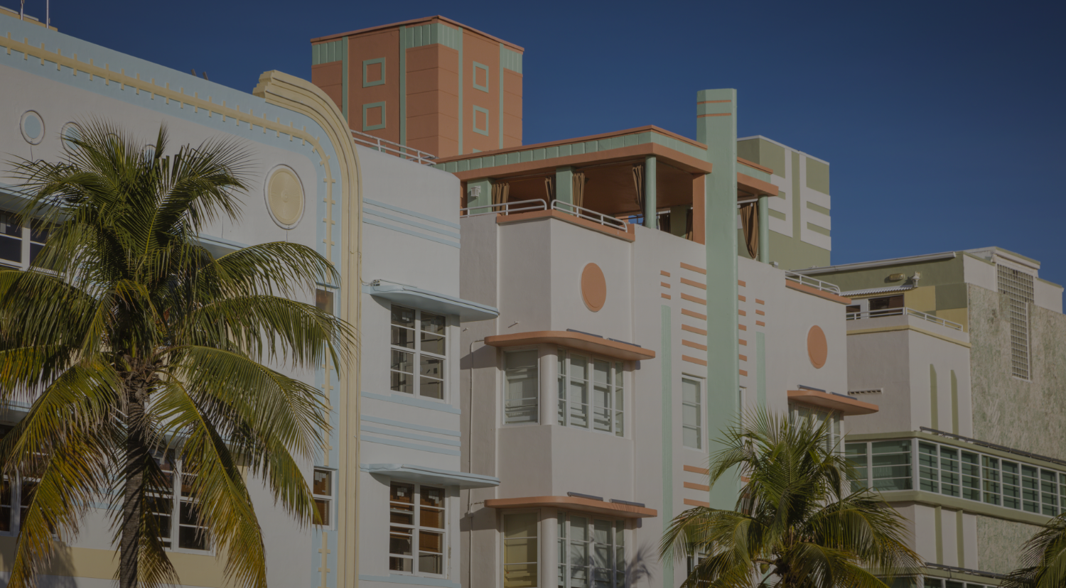 A multi-story building with ornate details and balconies, surrounded by palm trees under a clear sky.