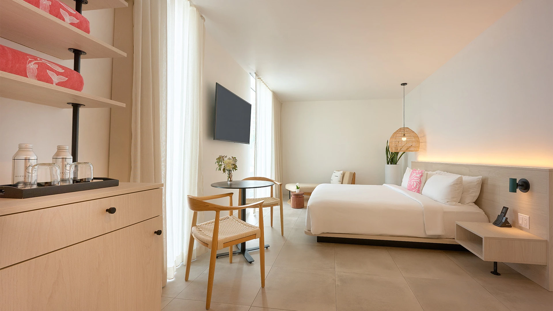 A hotel room with a bed, table, chair, and TV