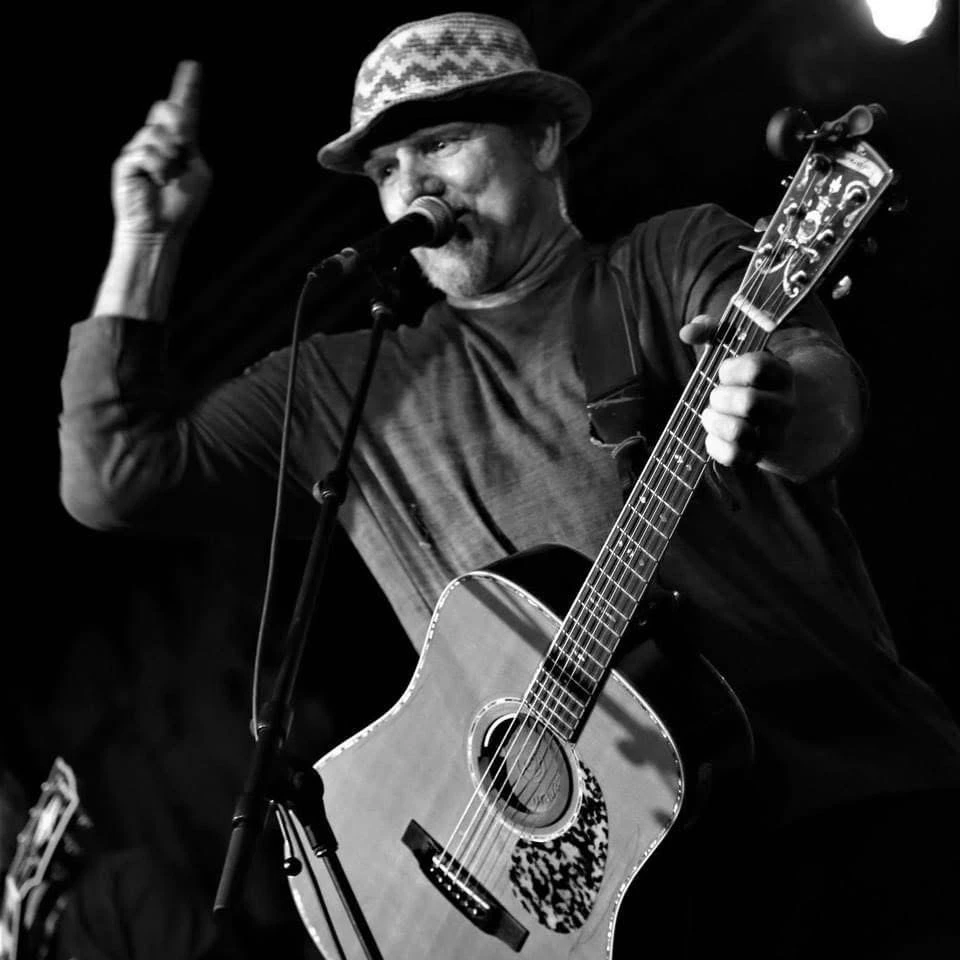a man holding a guitar and pointing up