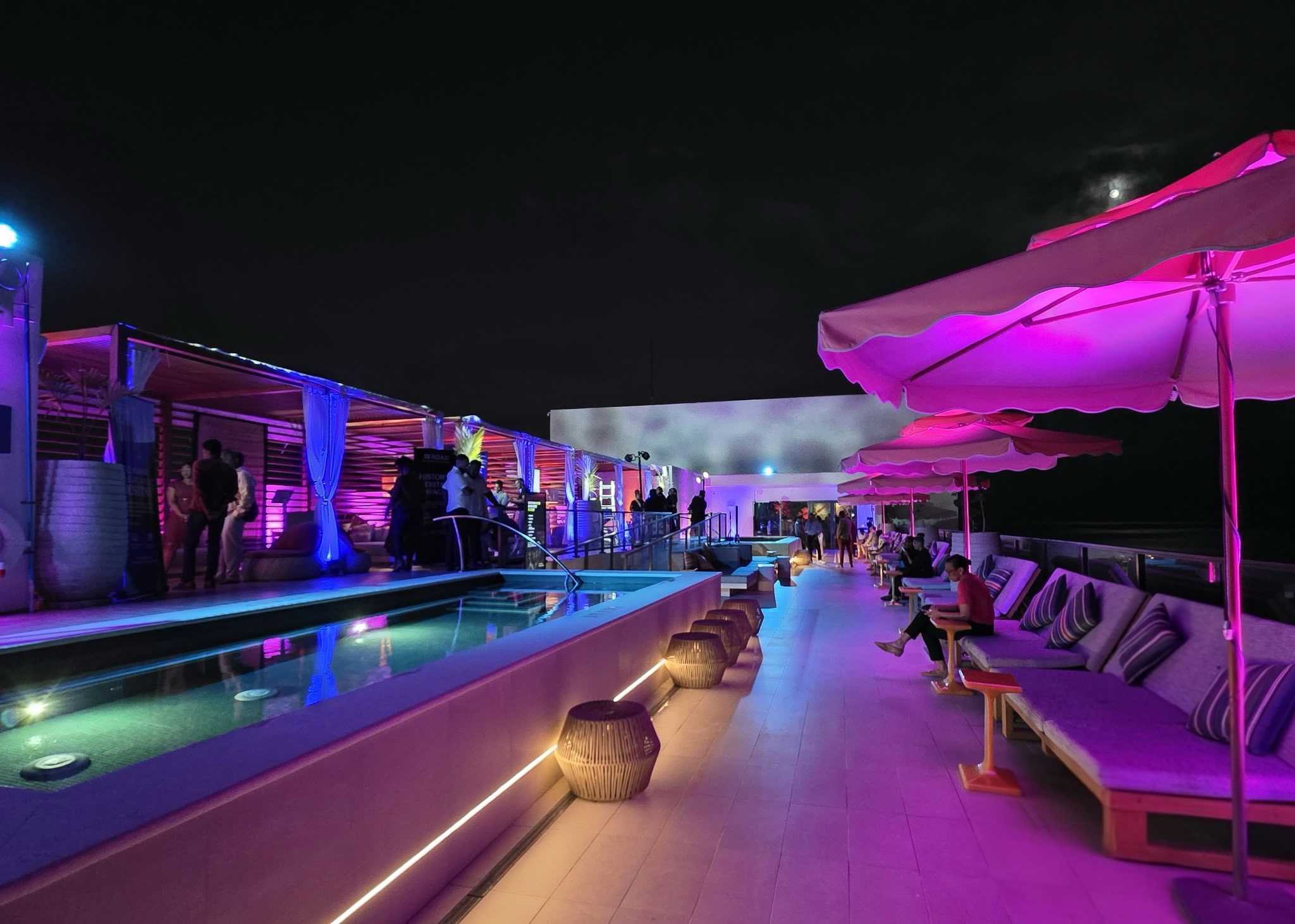 a pool with purple lights and people standing around