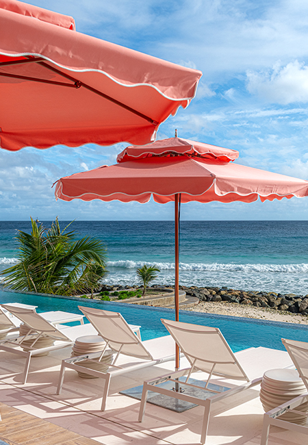 a pool with chairs and umbrellas by the ocean