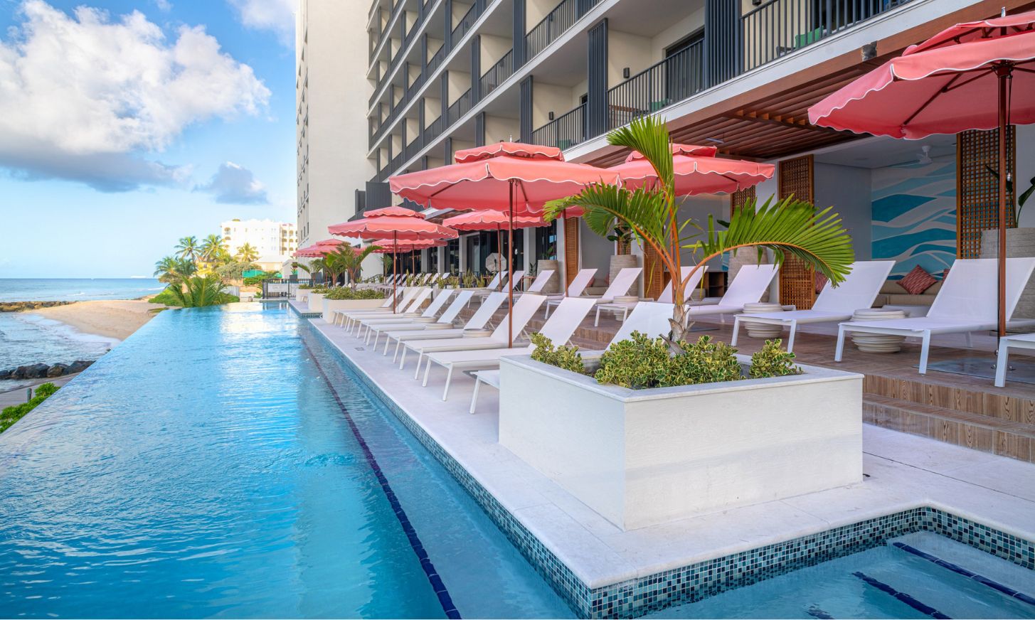 a pool with pink umbrellas and lounge chairs