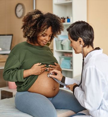 a doctor listening to a pregnant woman's belly