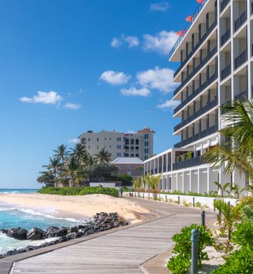 a walkway to a beach with a building and palm trees