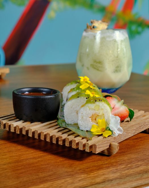 a sushi roll and a drink on a wood surface
