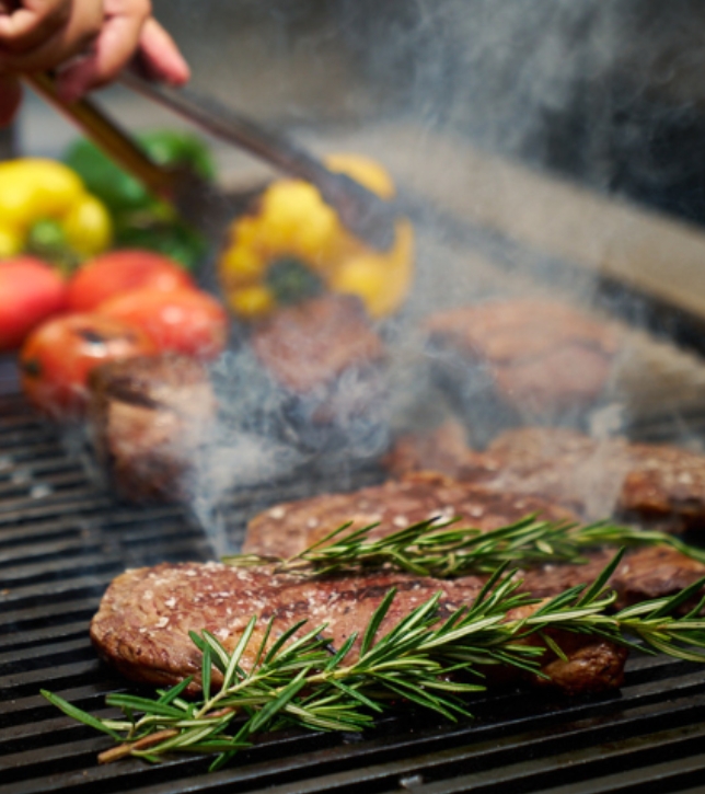meat on a grill with rosemary