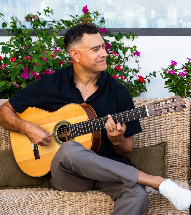 a man sitting on a couch playing a guitar