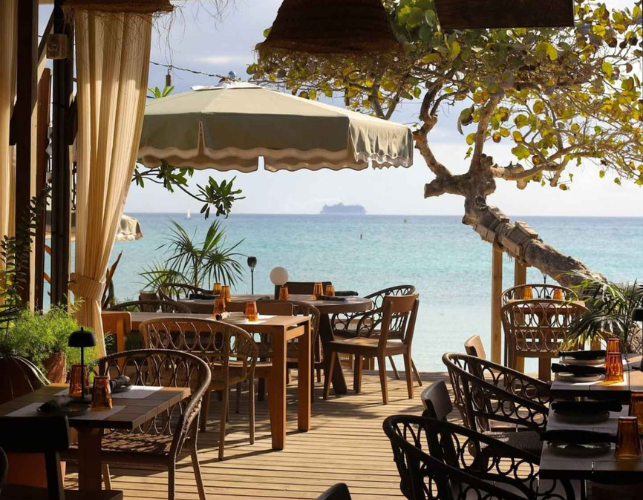 a restaurant with tables and chairs on a deck overlooking the ocean