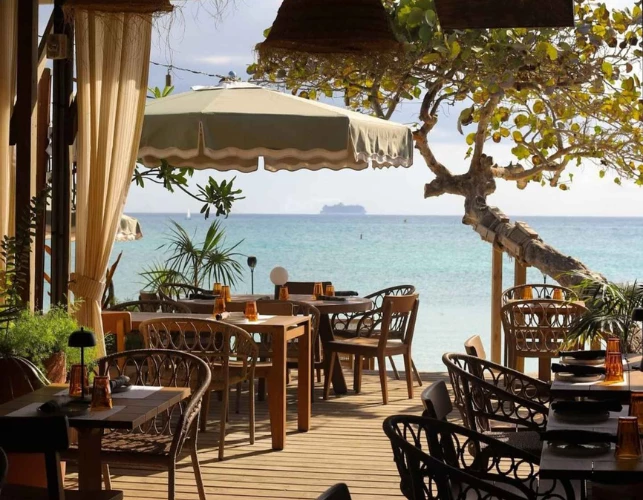 a restaurant with tables and chairs on a deck overlooking the ocean