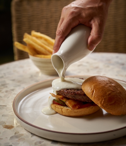 a person pouring milk onto a burger