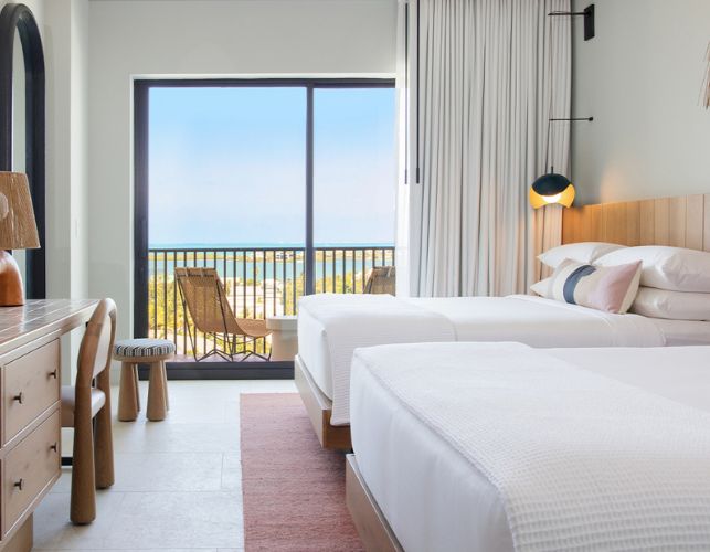 a room with two beds and a balcony overlooking the ocean