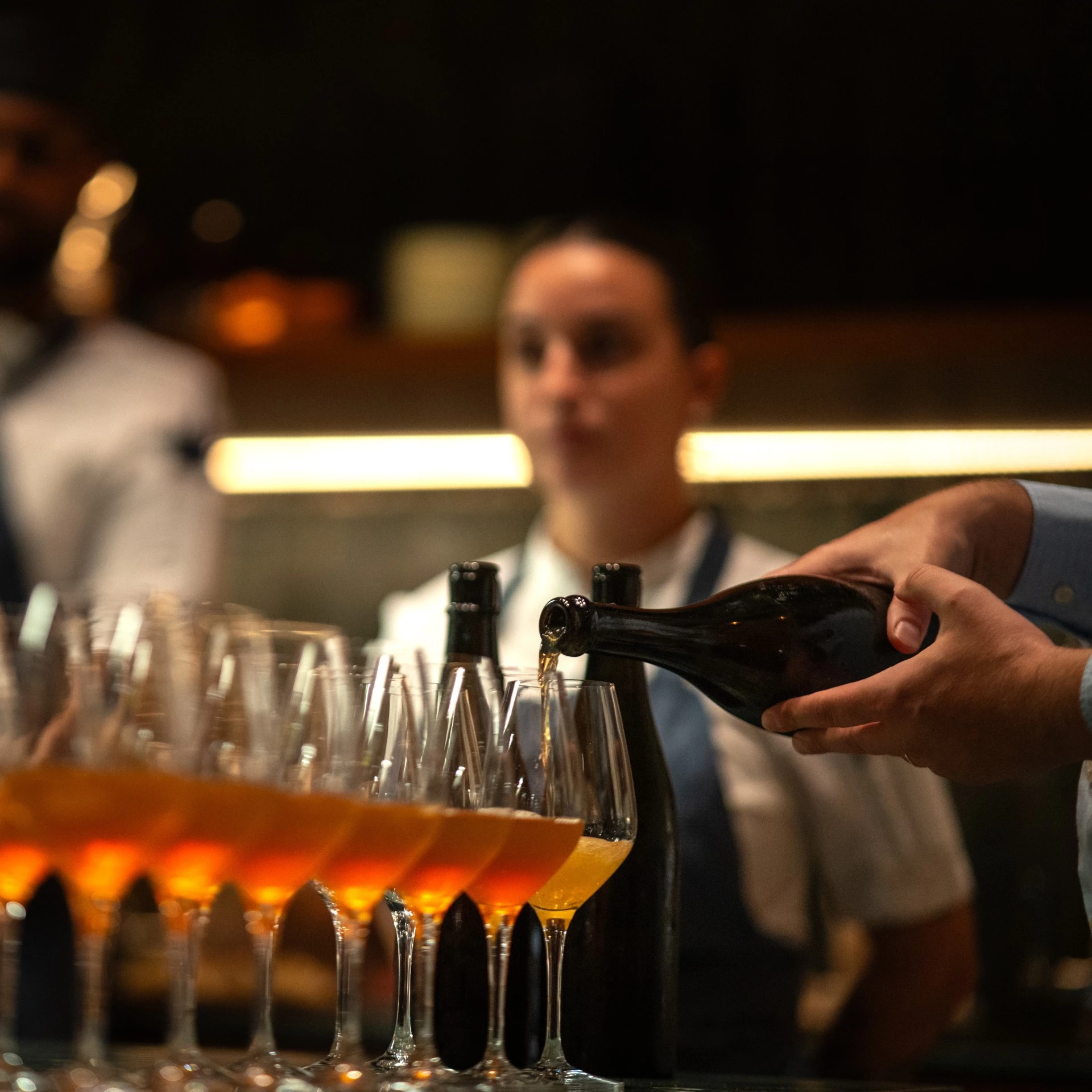 a person pouring wine into glasses