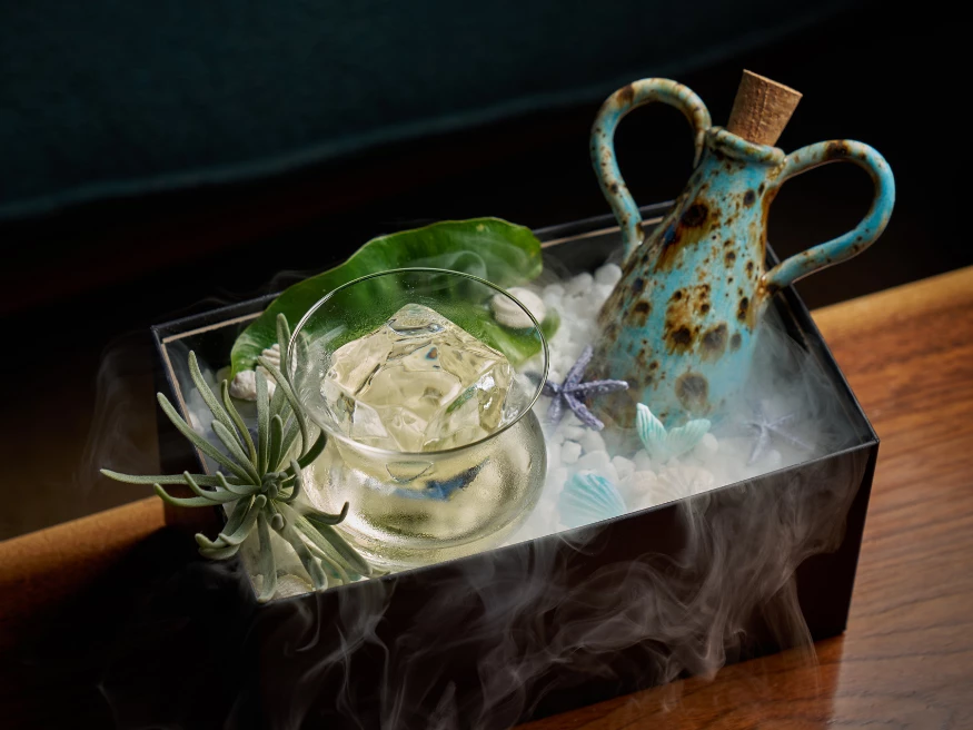 a container with a glass and a plant and a pitcher