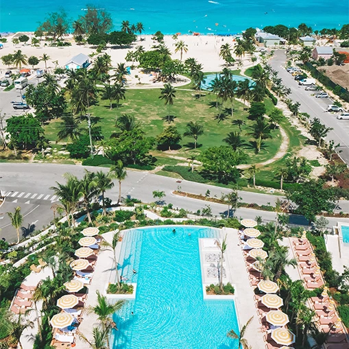 an aerial view of a resort with a pool and palm trees