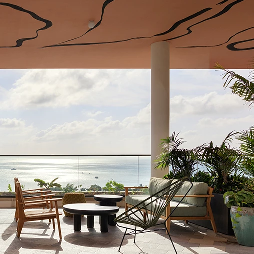 a patio with chairs and a table and a large window overlooking the ocean