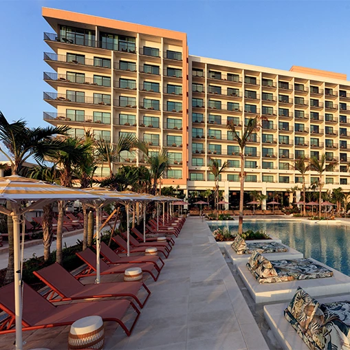 a pool with lounge chairs and umbrellas in front of a hotel