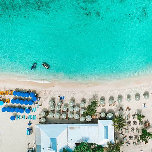 an aerial view of a beach with umbrellas and chairs