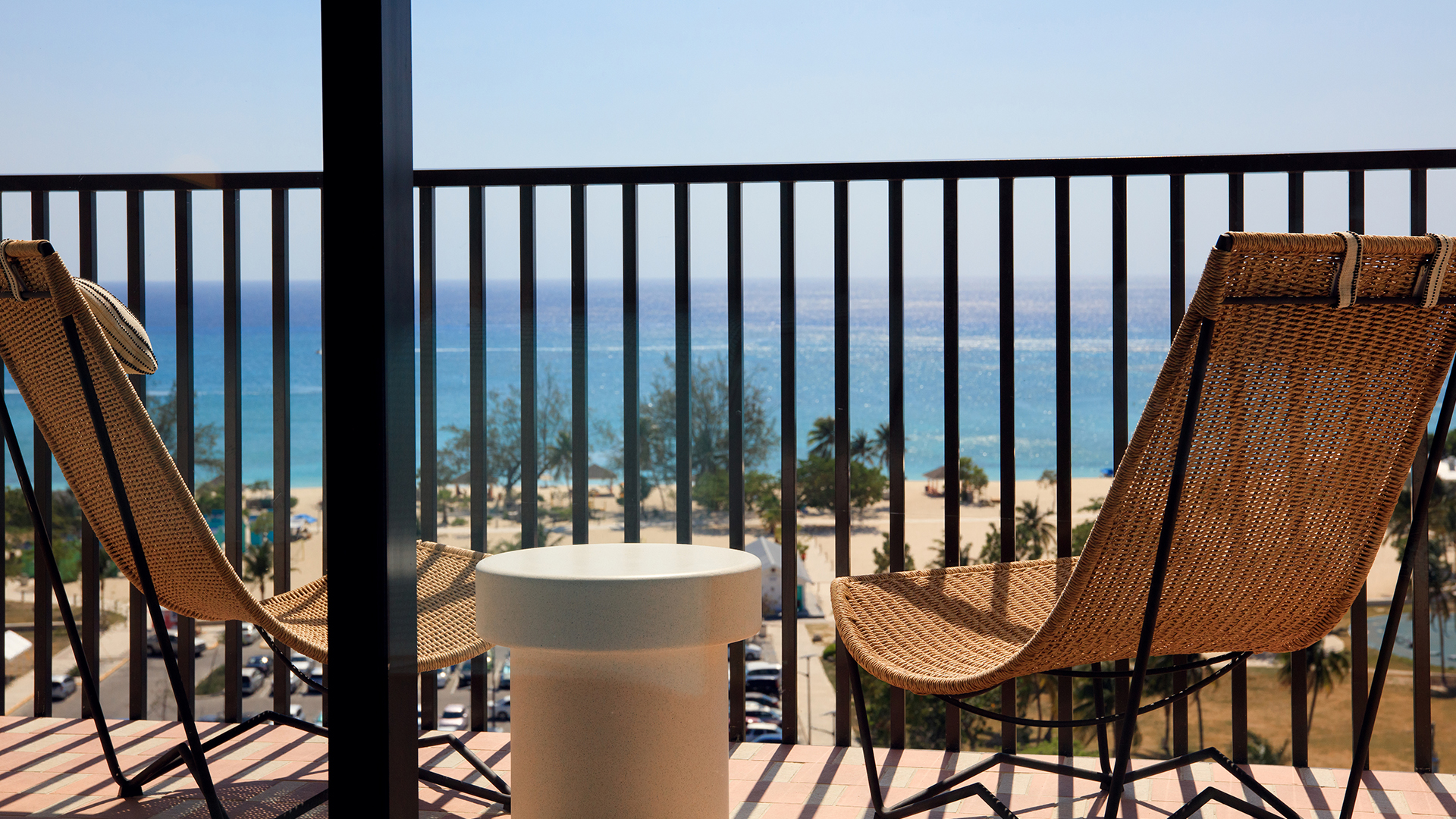 a chair and table on a balcony overlooking a beach