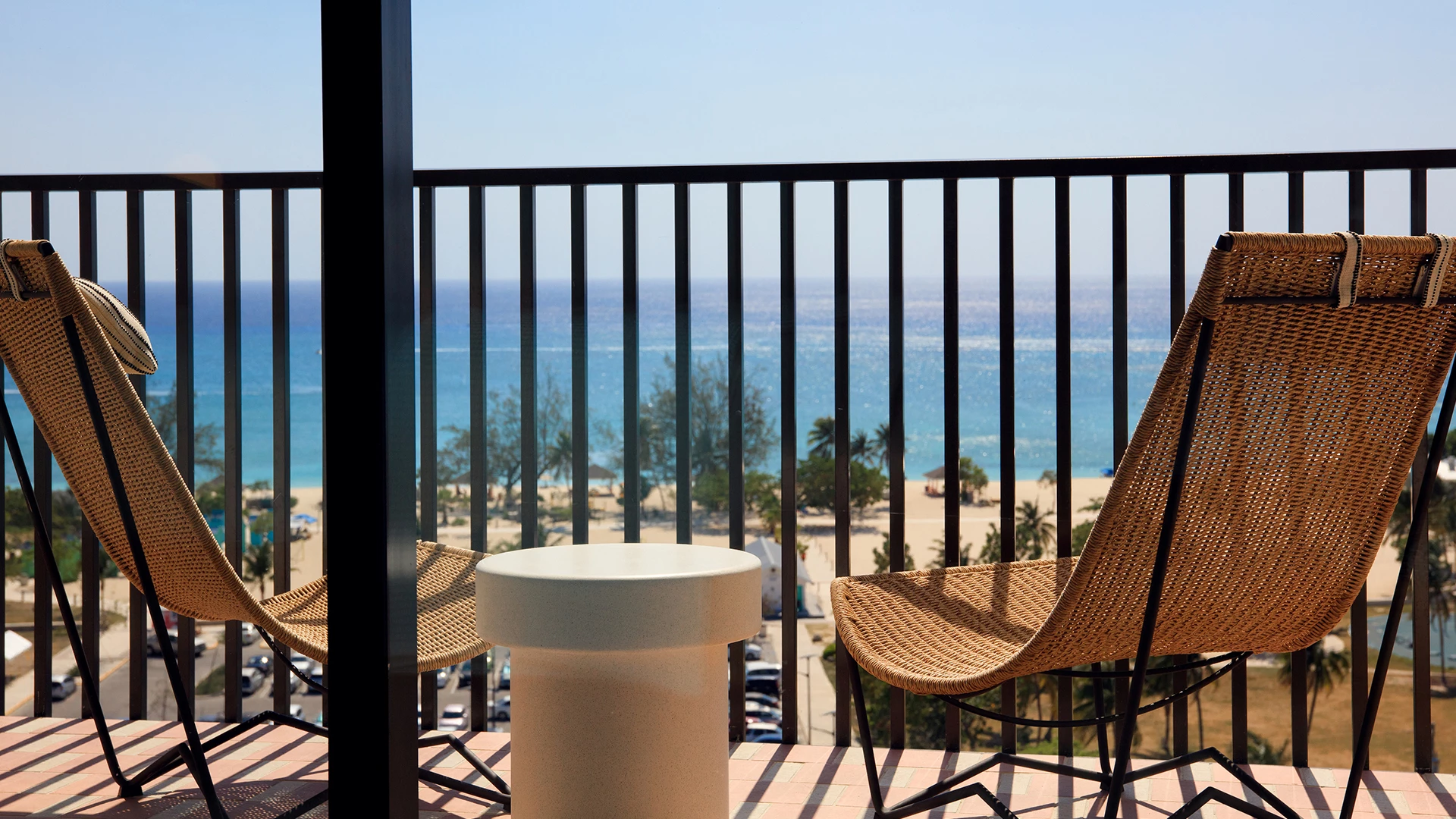 a chair and table on a balcony overlooking a beach