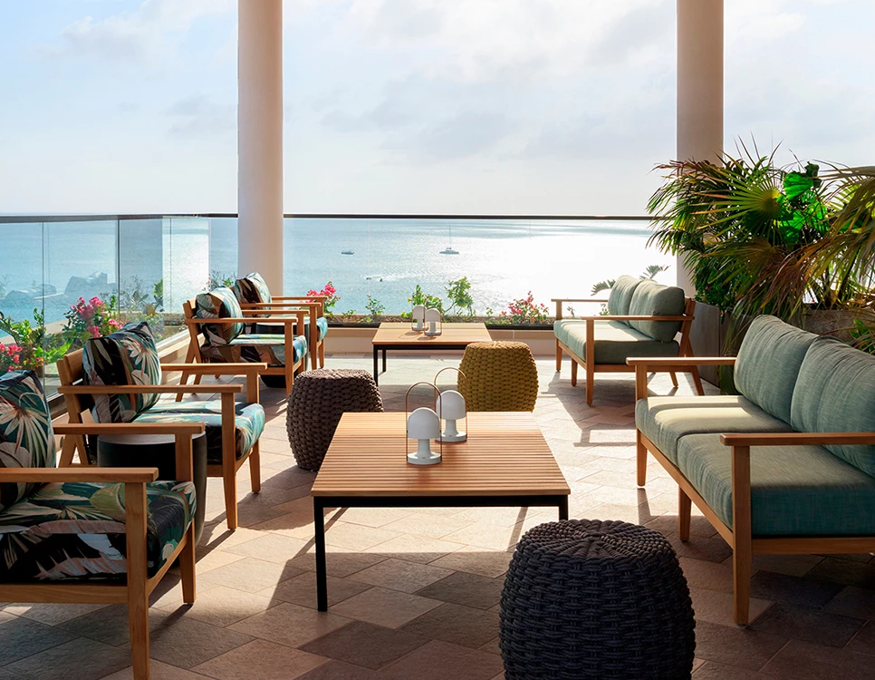 a patio with chairs and tables and a view of the ocean