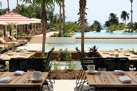 tables and chairs outside with a pool in the background