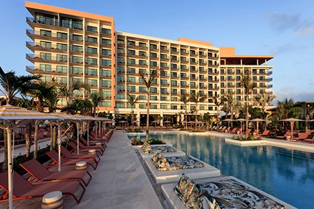 a pool with lounge chairs and lounge chairs in front of a hotel