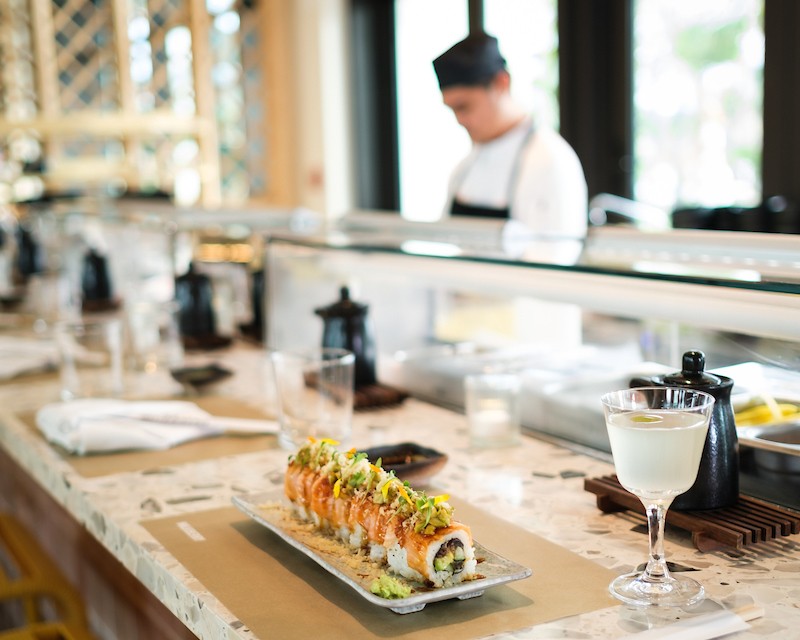 a sushi on a plate with a glass of liquid