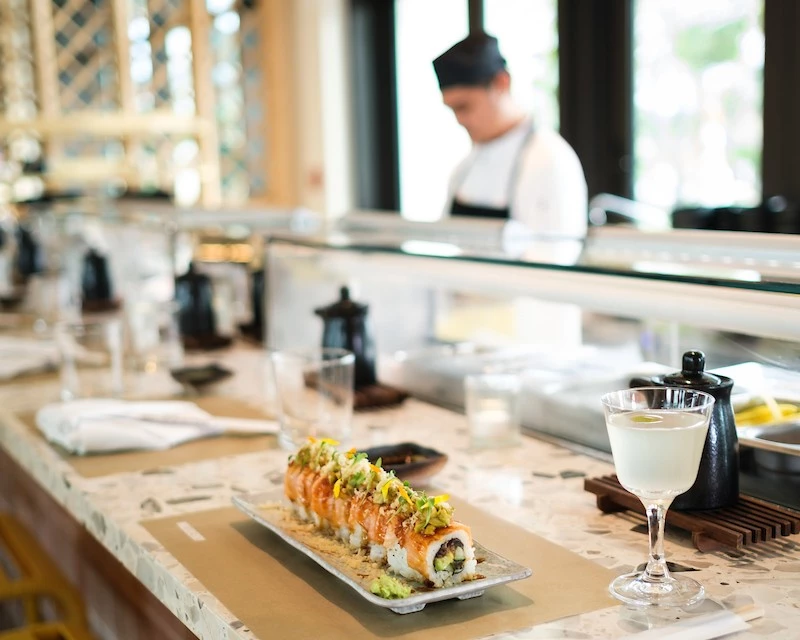 a sushi on a plate with a glass of liquid