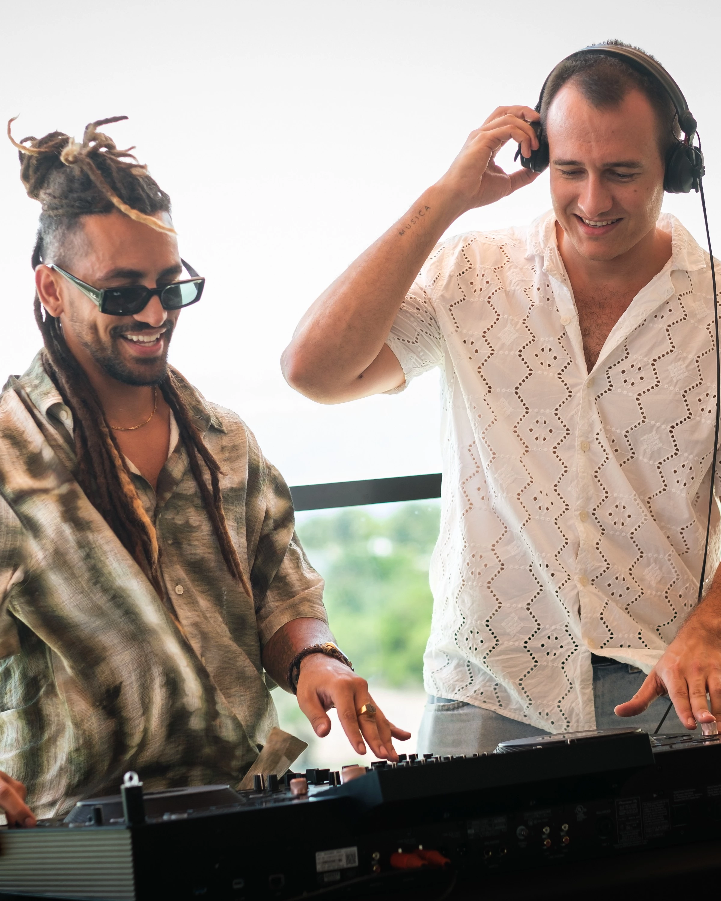 two men wearing headphones and standing next to a keyboard
