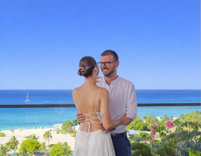 a man and woman standing on a balcony with a beach and water in the background