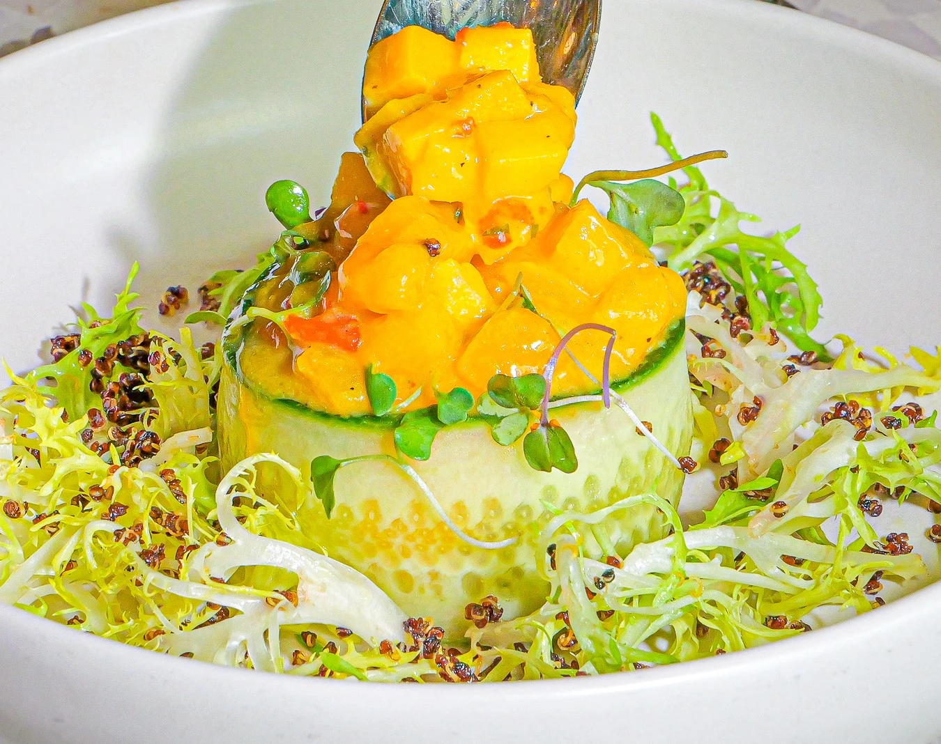 a cucumber and mango salad with a spoon