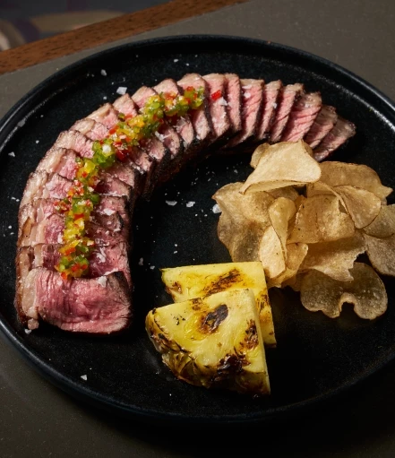 a plate of food with a slice of meat and chips