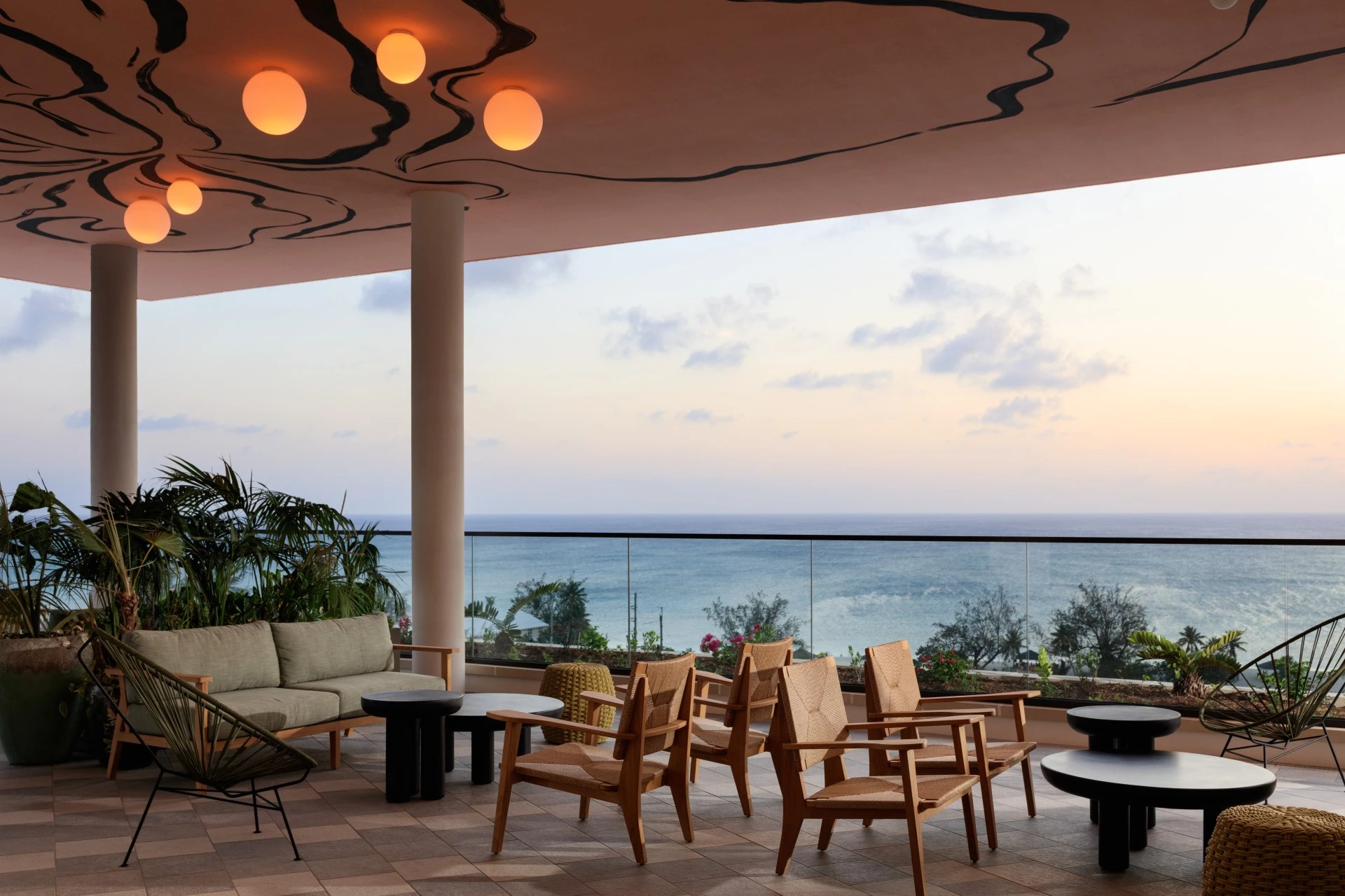 a patio with chairs and a table and a large railing overlooking the ocean