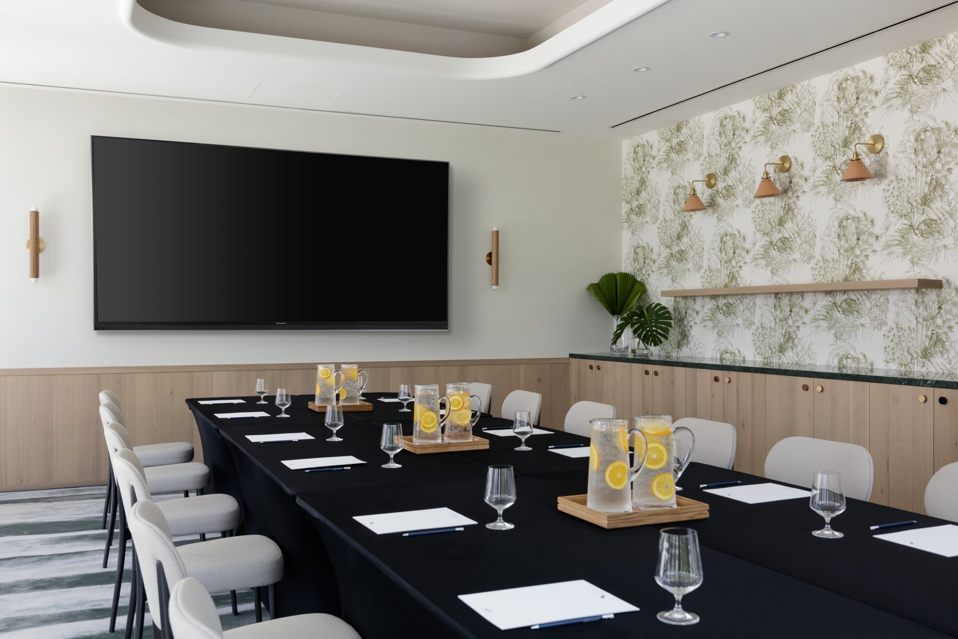 a room with a large black table with glasses and a black screen