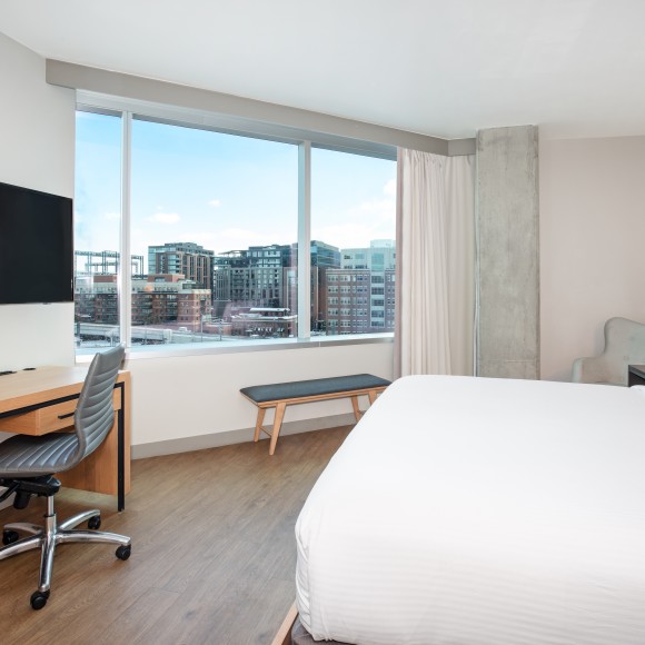 a room with a bed and a desk and a television