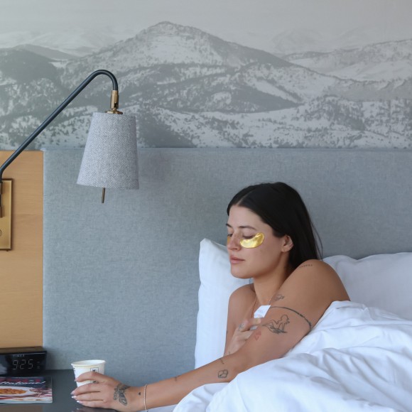 a woman lying in bed with a cup of coffee