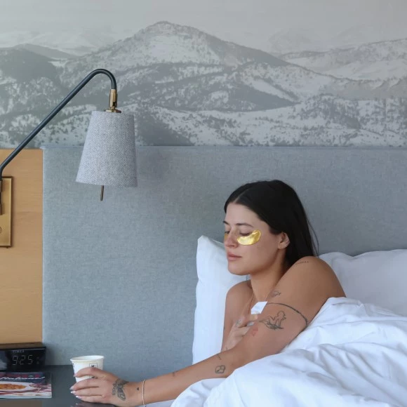 a woman lying in bed with a cup of coffee