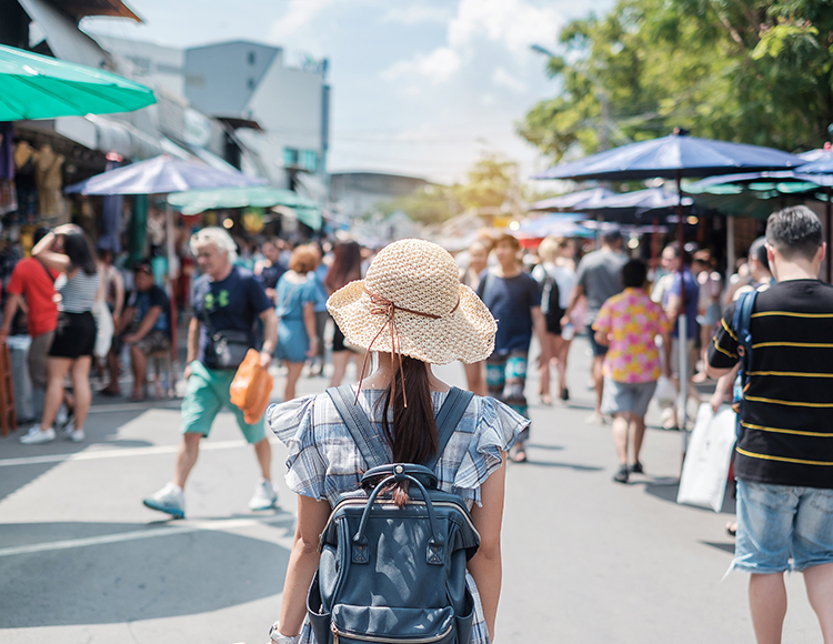 a woman wearing a hat and backpack walking down a street