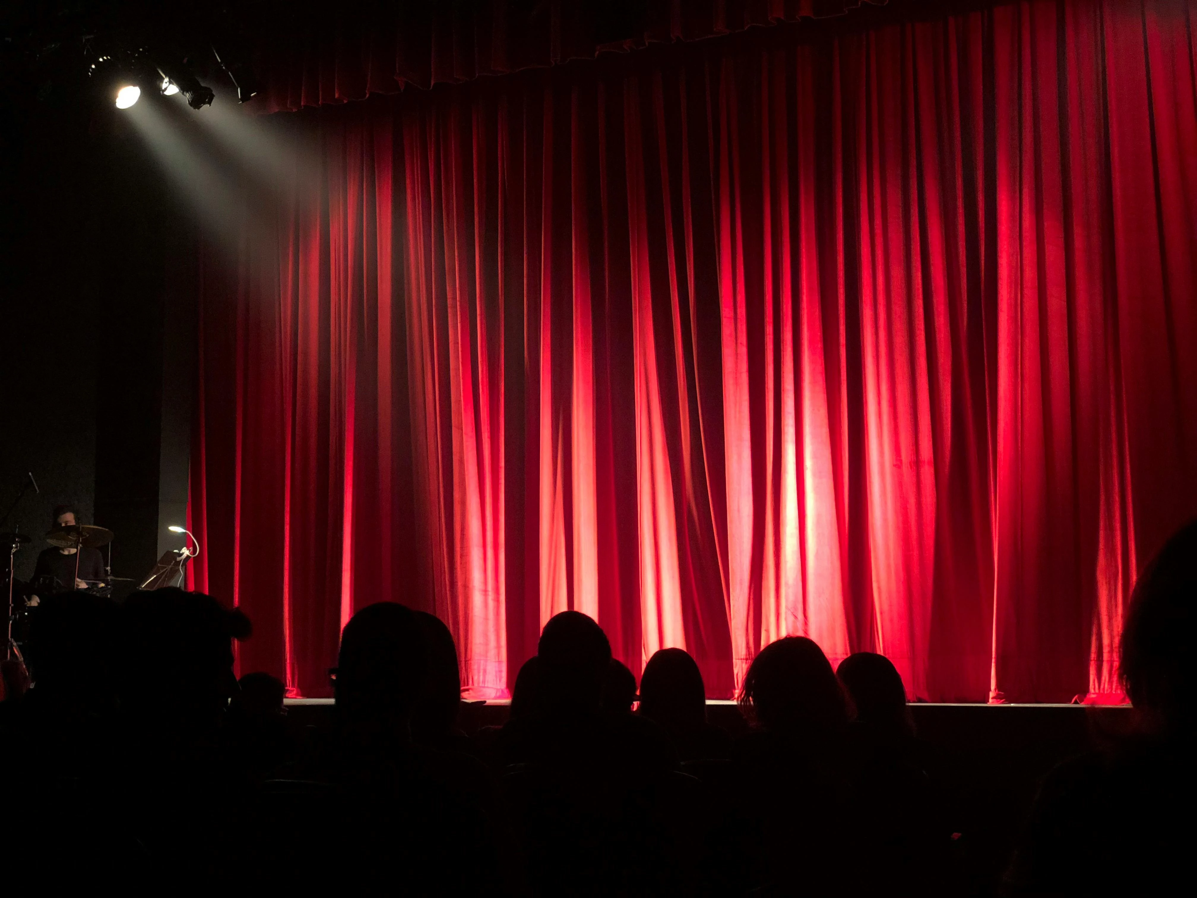a red curtain with a crowd watching a performance