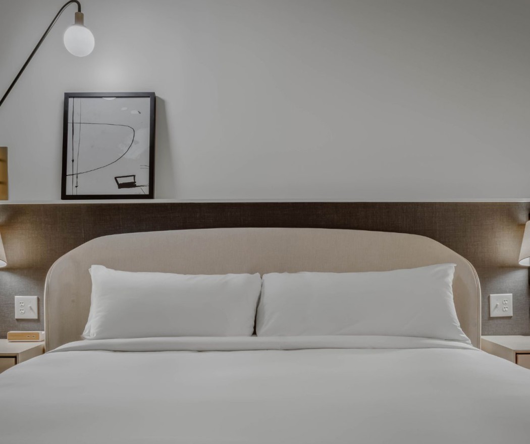 a bed with a lamp and a picture on the wall