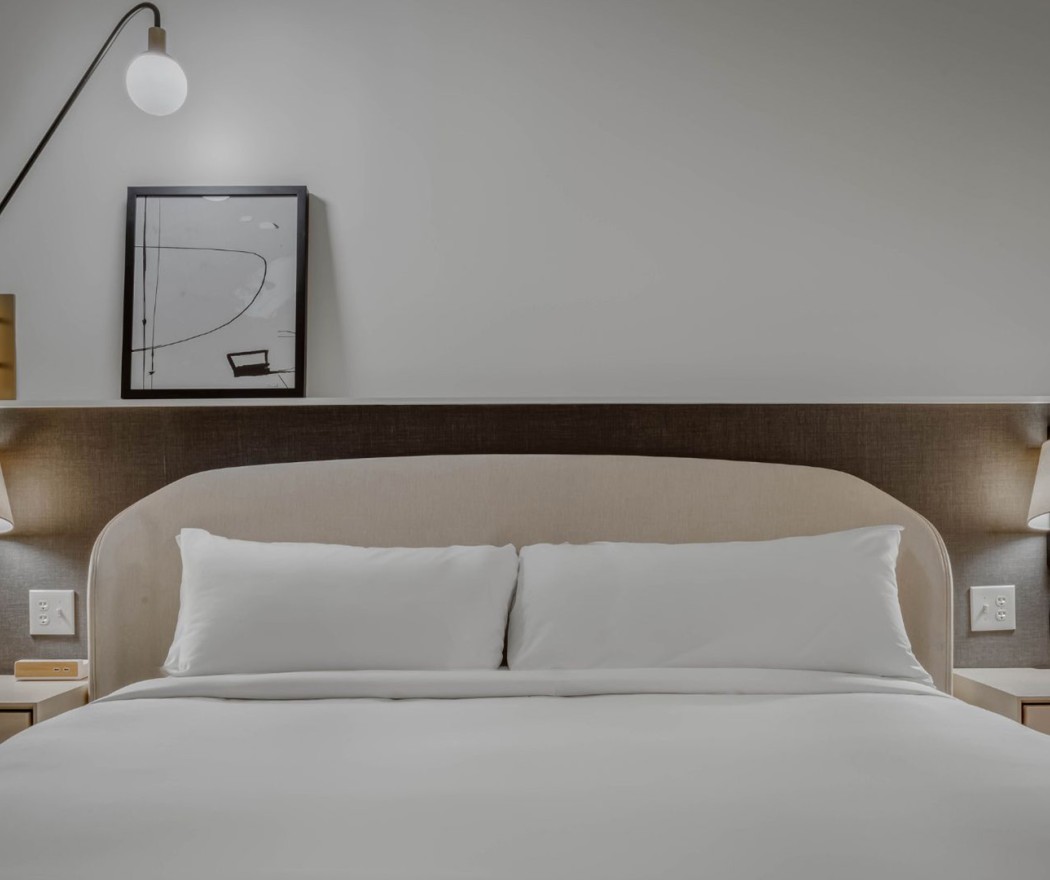 a bed with a lamp and a picture on the wall