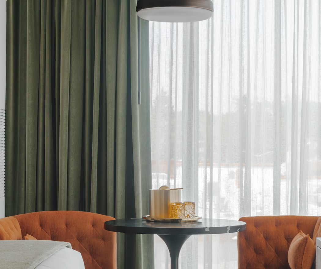 a table with a round object on it next to a bed and curtains