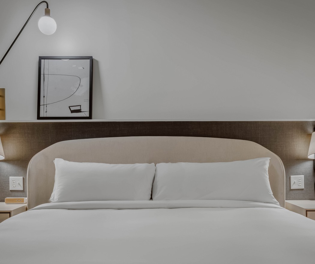 a bed with a lamp and a picture on the wall