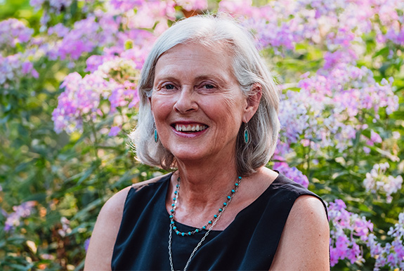 a woman smiling in front of purple flowers