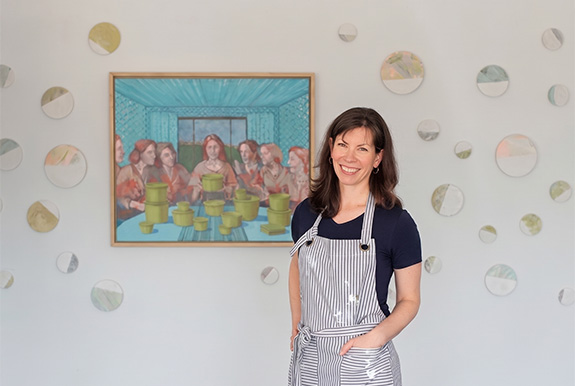 a woman in an apron standing in front of a painting